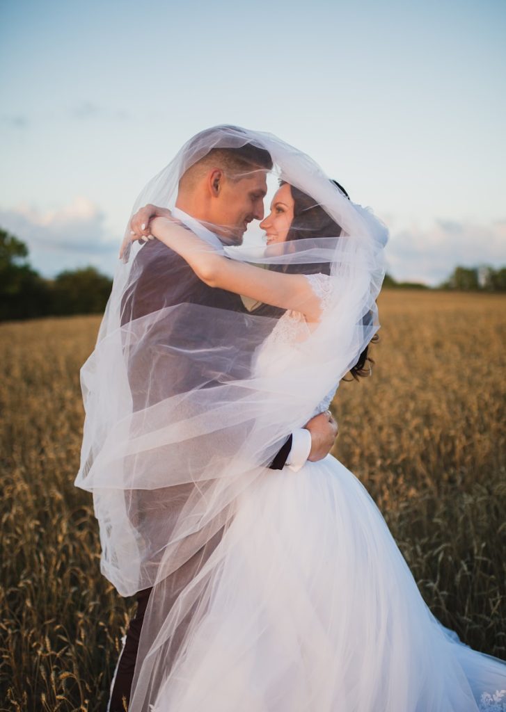 CONTACTAR CON BODAS Y EVENTOS LINDSTROEM smiling newly wed couple about to kiss in green field